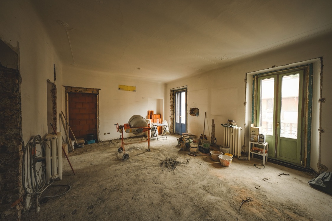 A room mid-renovation with building materials and a cement mixer