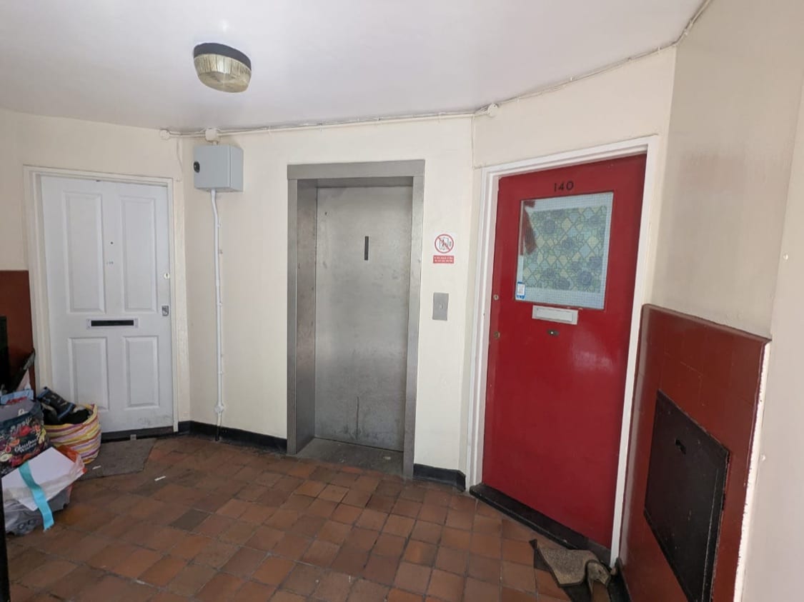 Communal landing outside the Innes Gardens flat showing the original red front door before any work started