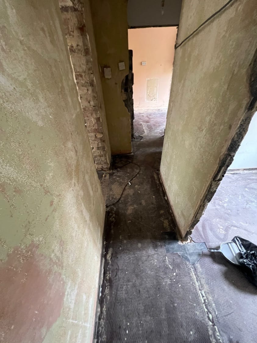 Stripped corridor with exposed brick pier, doors removed, at the Innes Gardens flat