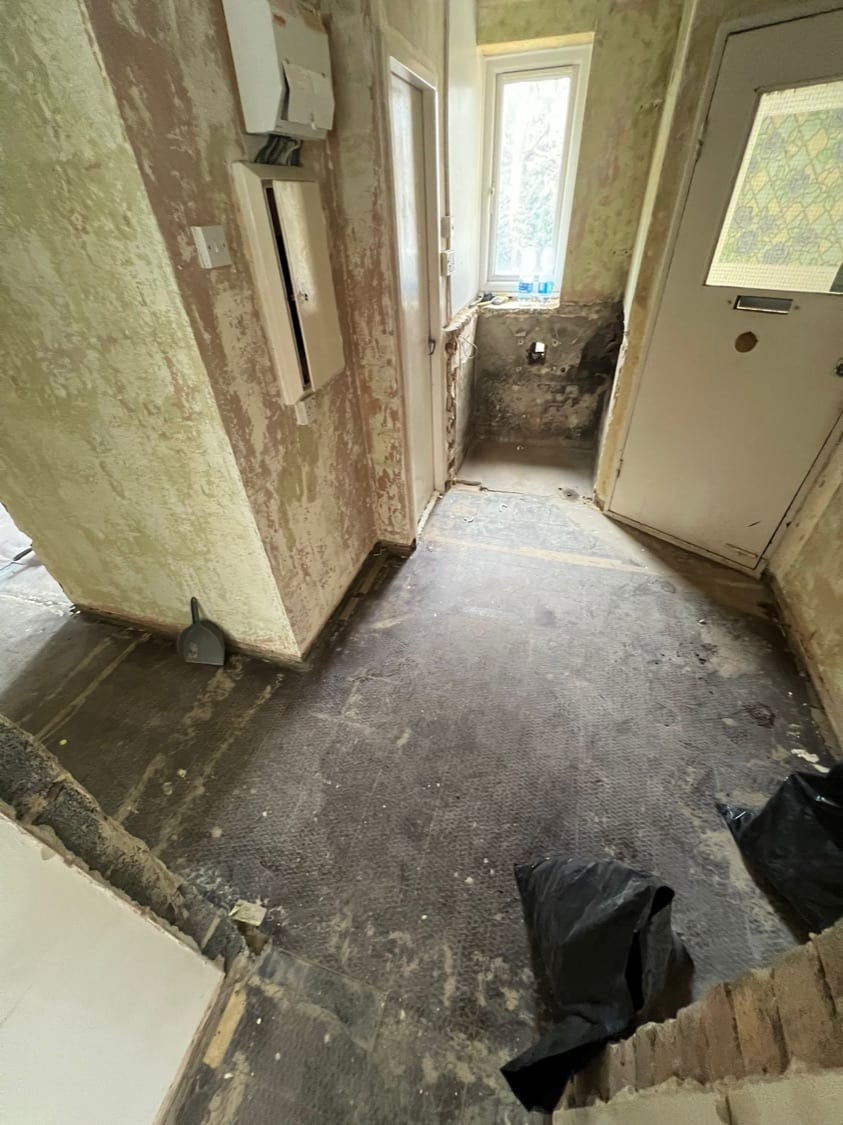Stripped hallway showing the original front door and meter cupboard at the Innes Gardens flat