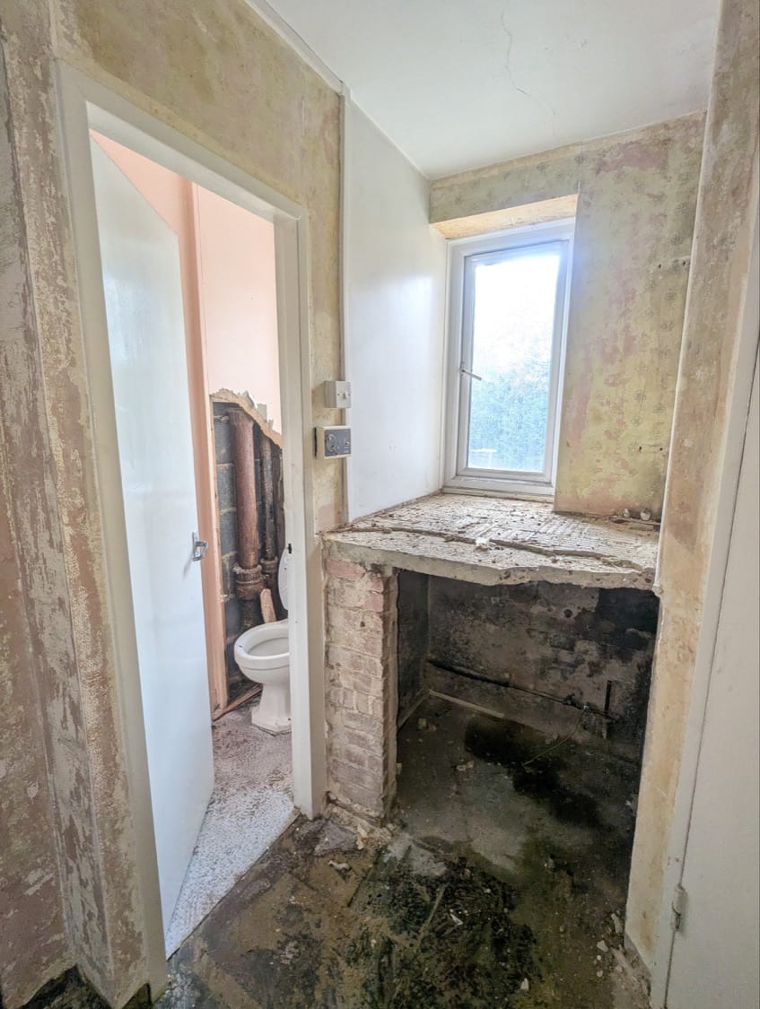 Toilet room with boxing removed, showing the boiler cupboard wall due to be merged into a second bathroom